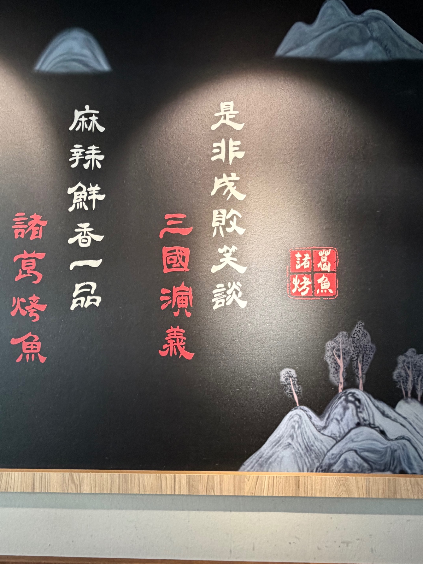Kalligrafie-Wandbild mit Gedicht ‚麻辣鲜香一品 · 诸葛烤鱼' vor Berglandschaft