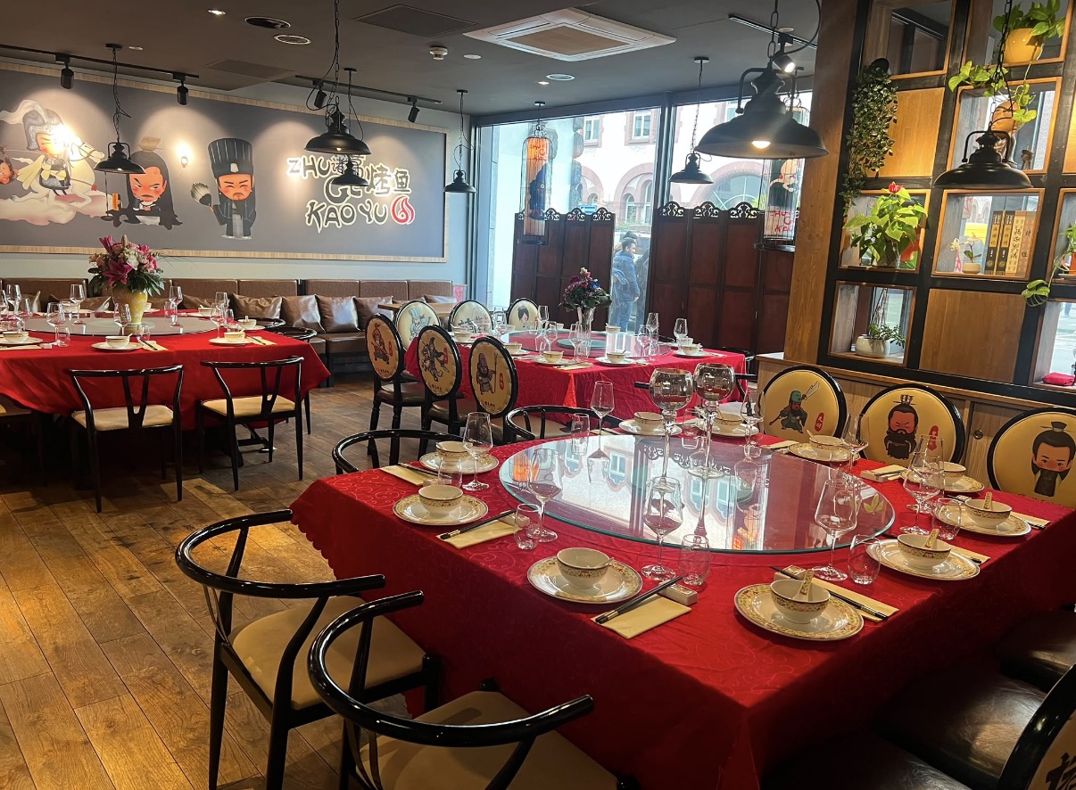 Festlich gedeckte runde Tische mit roter Tischdecke und Charakter-Stühlen im Restaurant 诸葛烤鱼