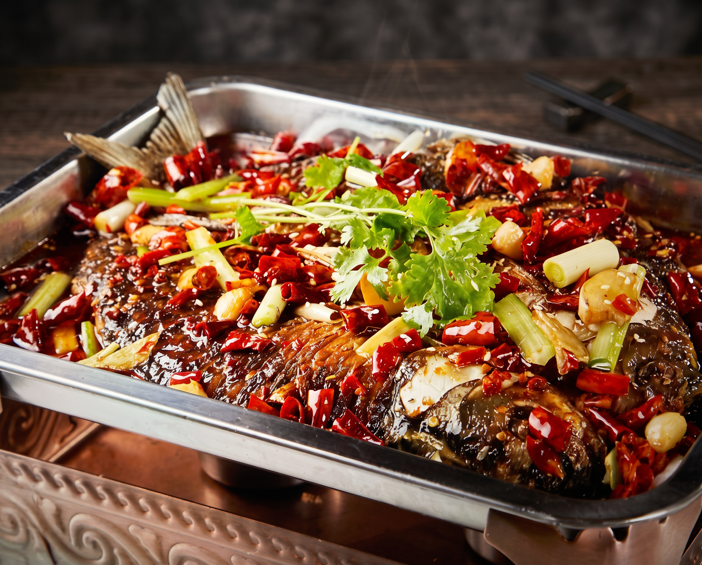 Sichuan-Grillfisch im traditionellen Kupfergefäß mit Chilis, Frühlingszwiebeln und Gewürzen